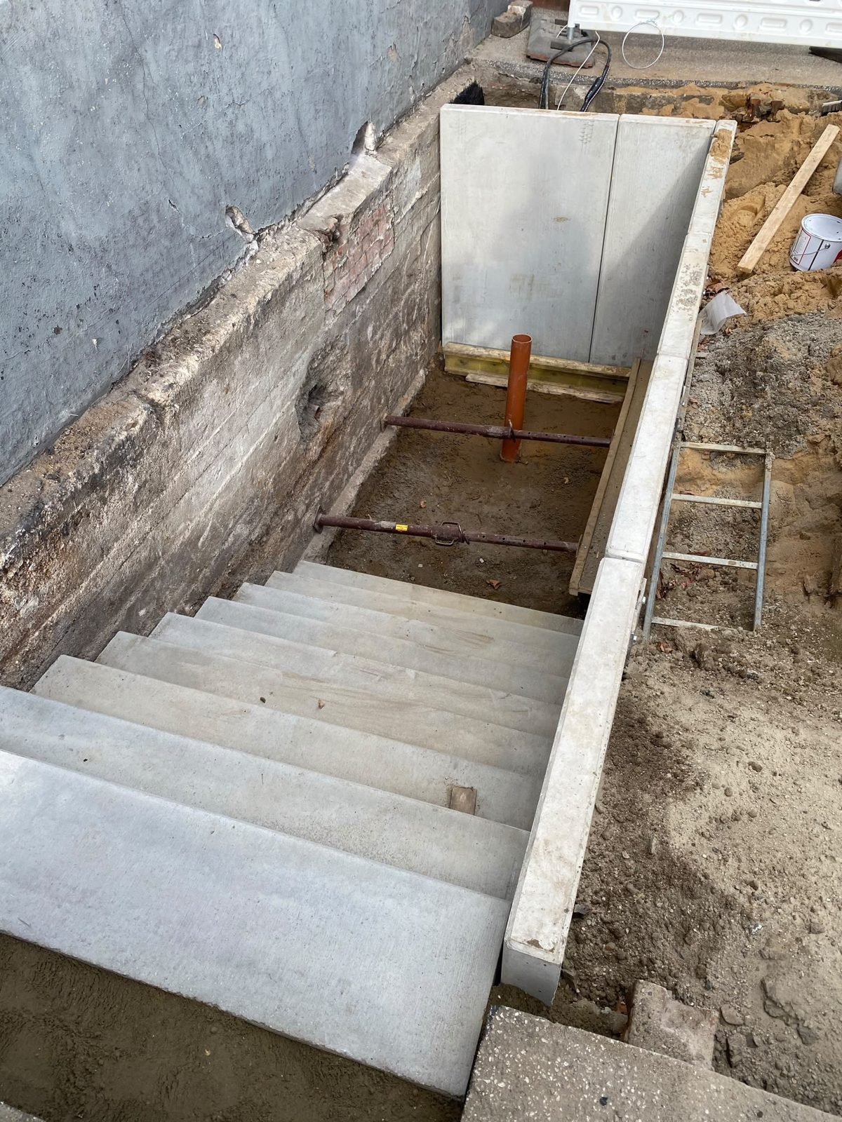 Neue Treppenanlage – Bauphase: Betontreppe im Bau mit Abstützung im ausgehobenen Treppenschacht