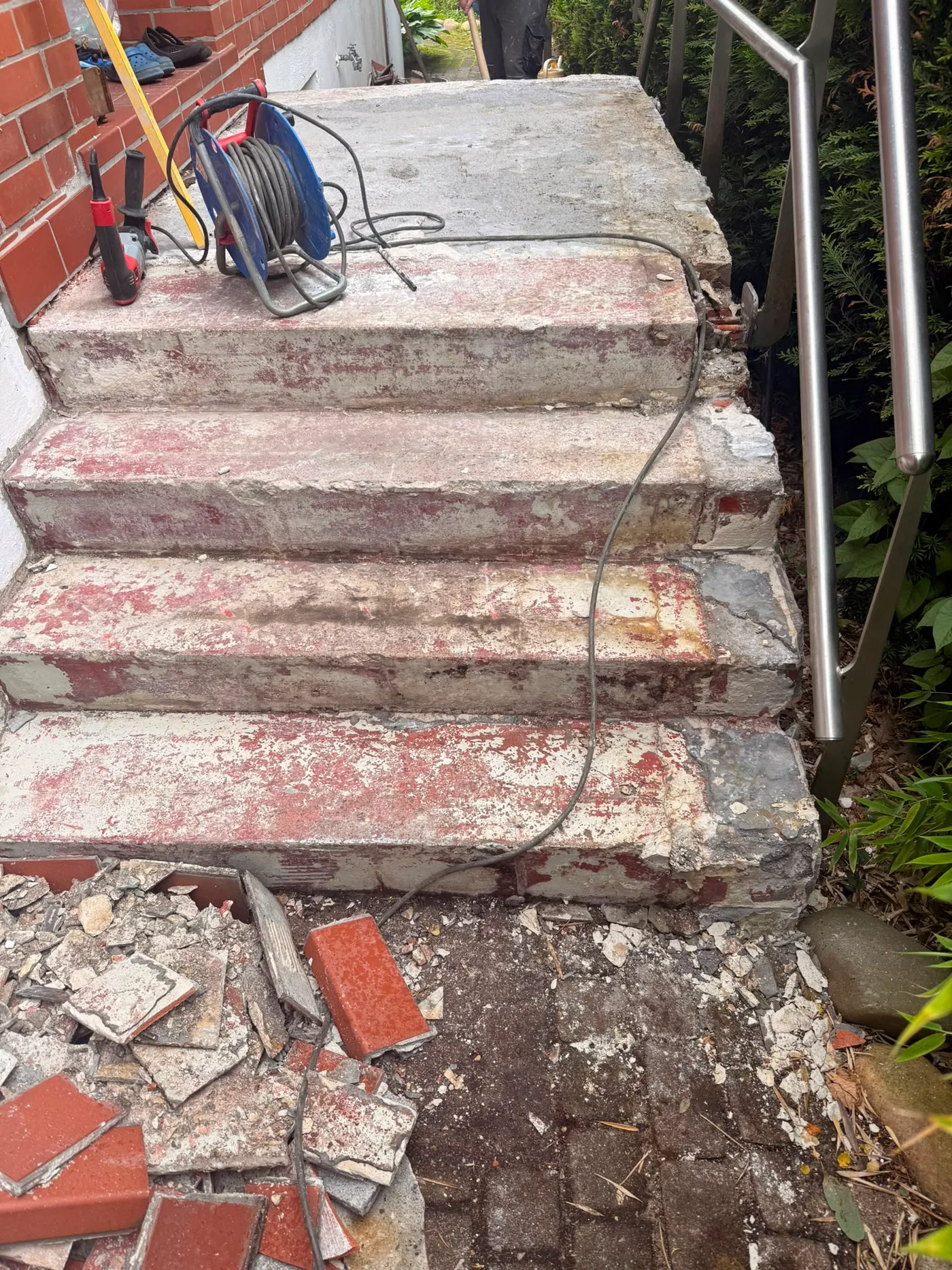 Treppeneingang – Vorher: abgenutzte rote Betonstufen mit Werkzeug und Bauschutt