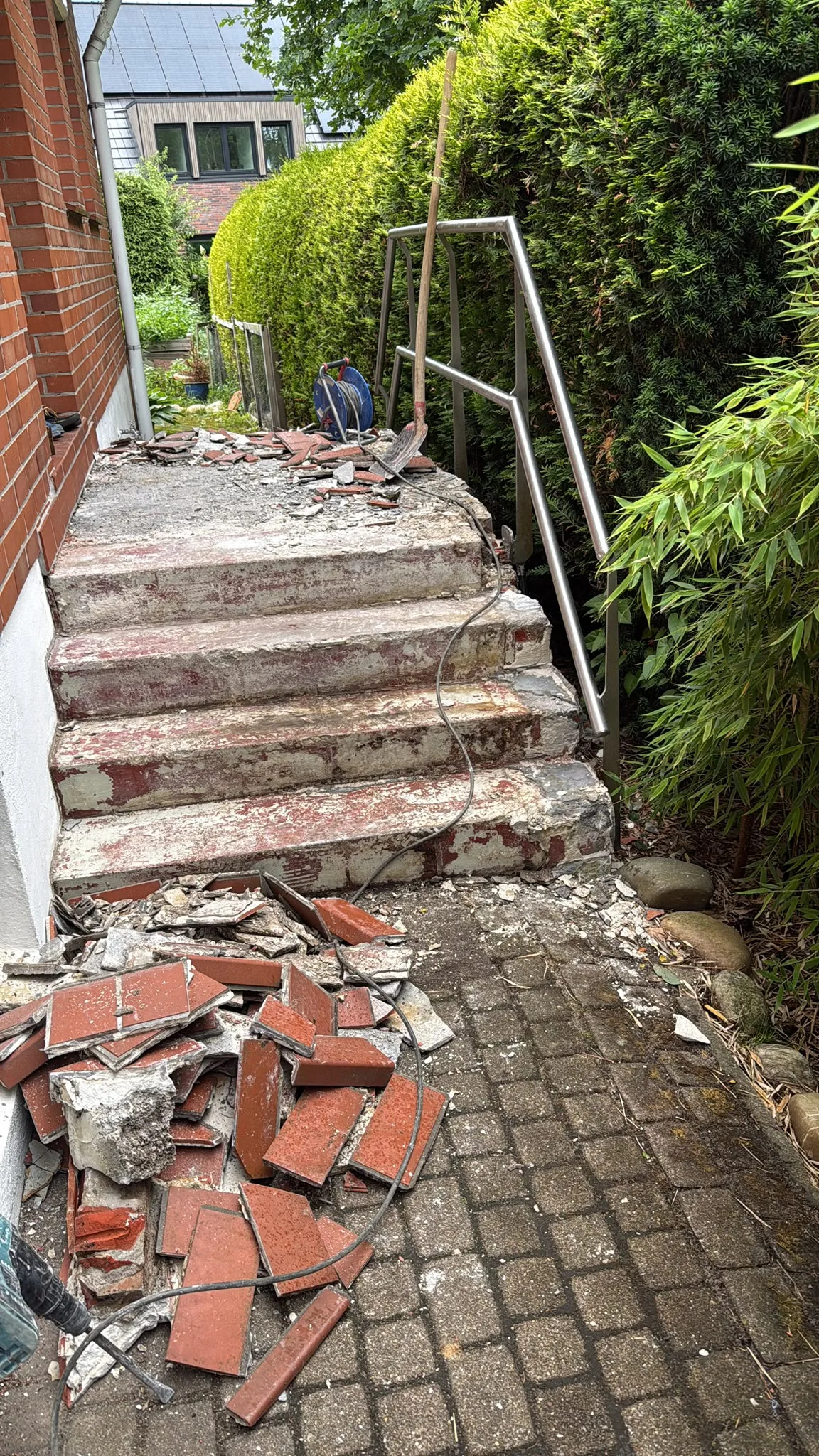 Treppeneingang – Vorher: abgebrochene rote Betonplatten in der Schrägansicht